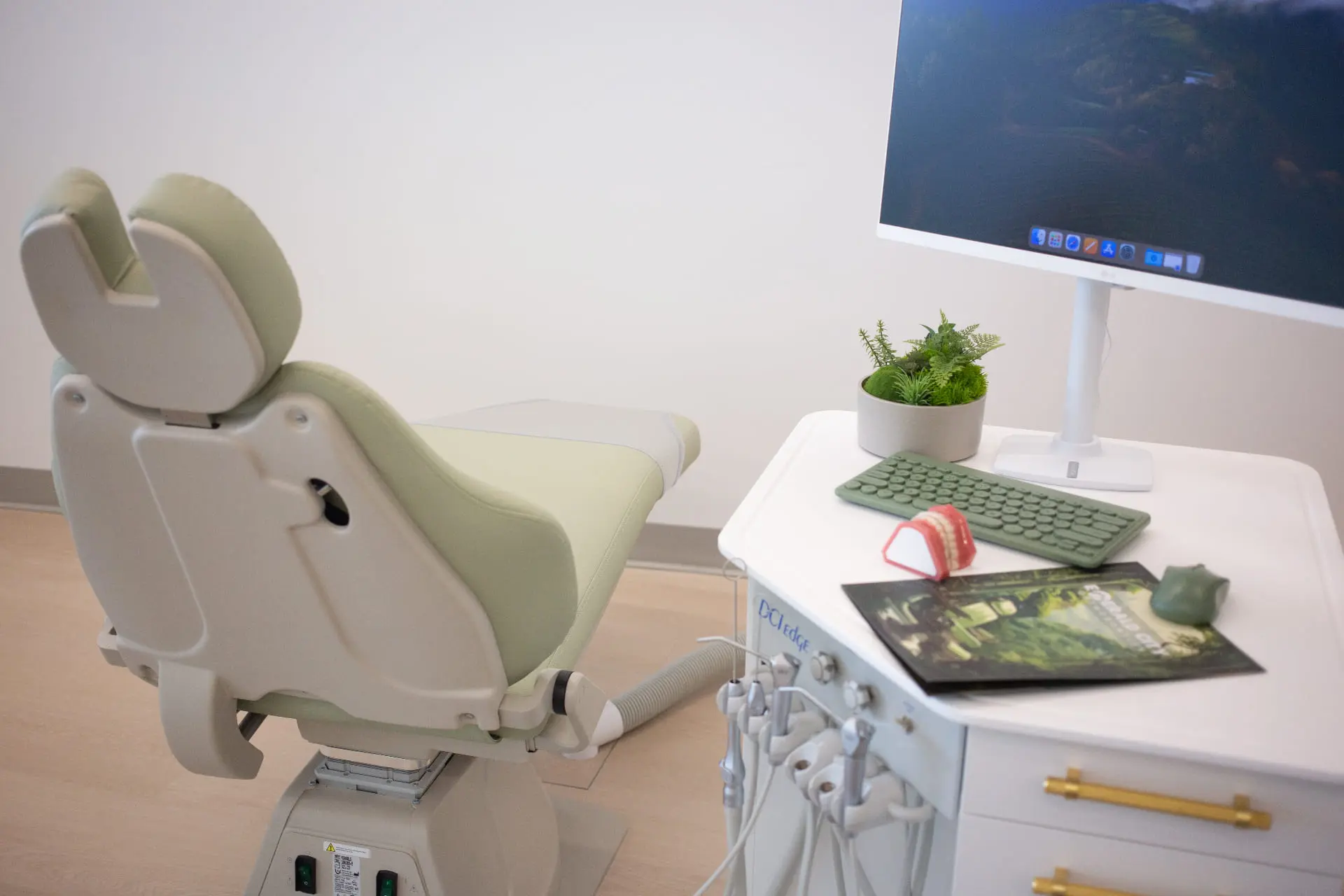 At Emerald City Orthodontics in Kirkland WA, a dentist chair, monitor, dental tray, teeth model, and plant create a modern office.