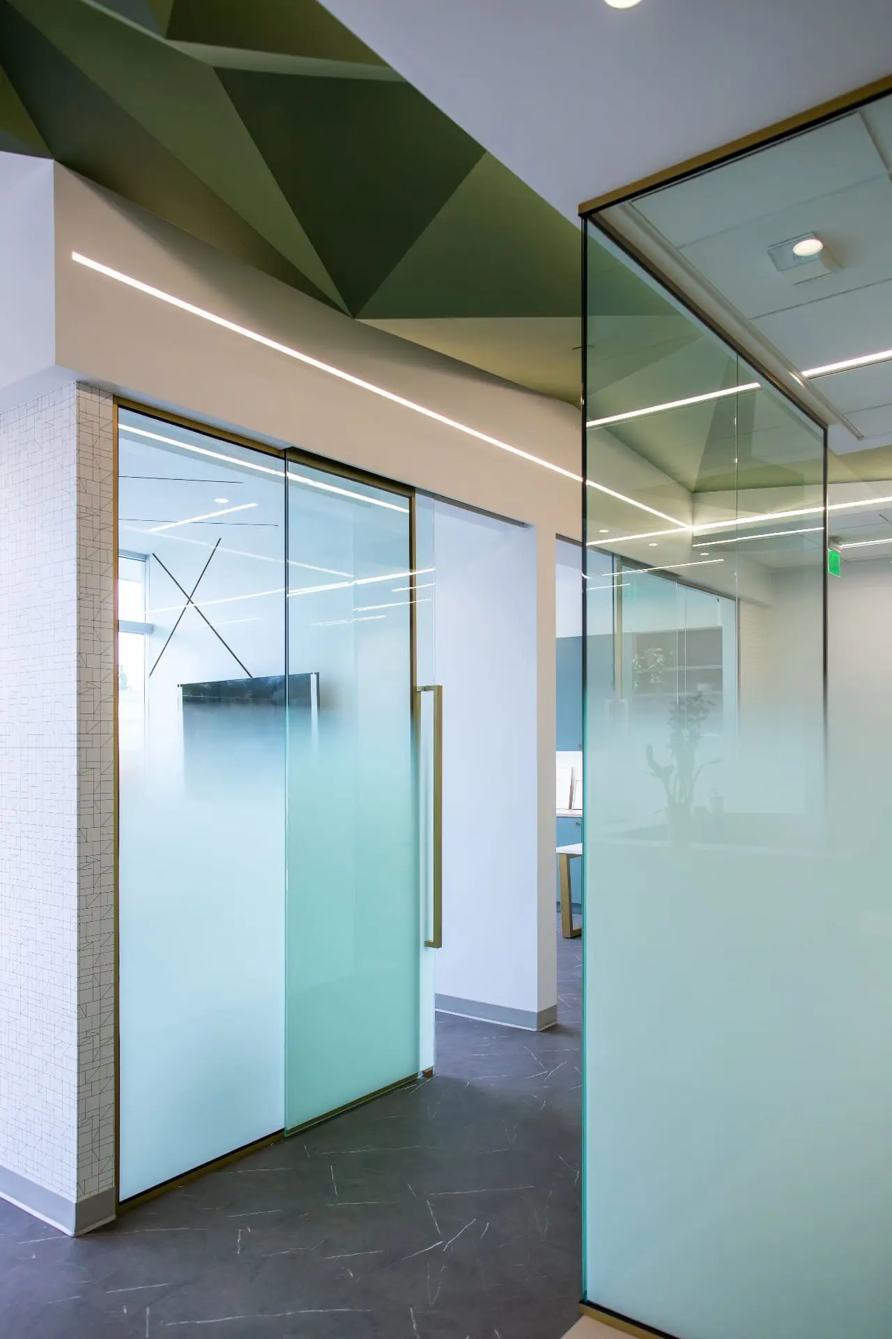 Sleek modern office at Emerald City Orthodontics in Kirkland WA, features frosted glass walls, geometric ceiling, and stylish lights.