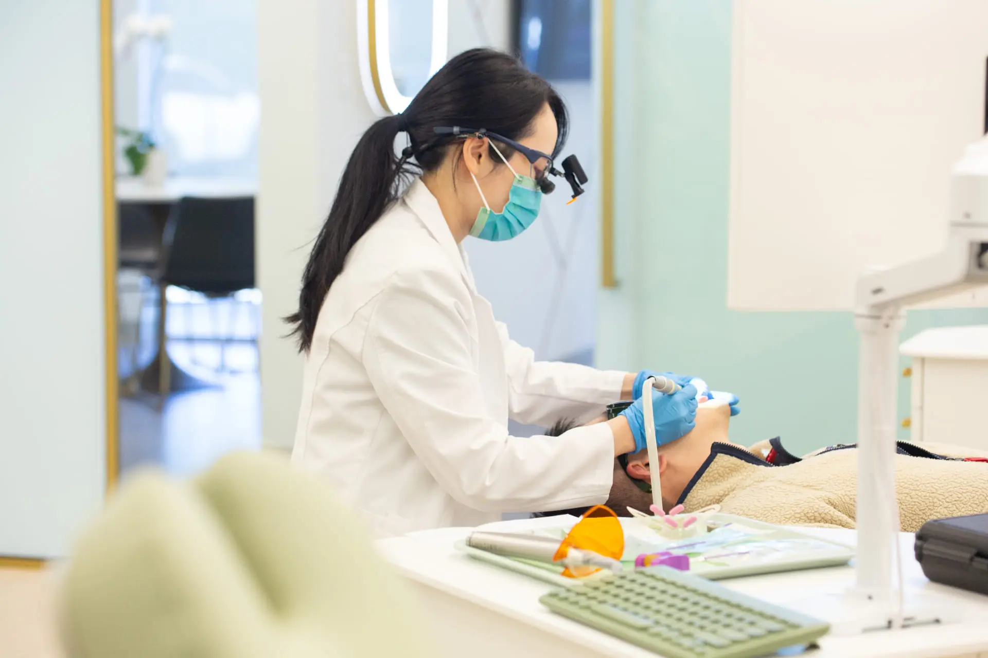 At Emerald City Orthodontics in Kirkland WA, a masked dentist treats a patient in a modern dental chair.