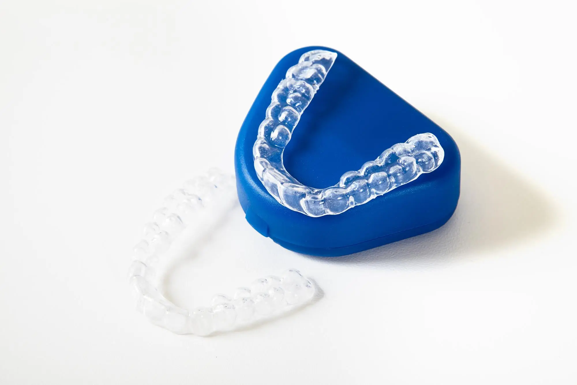 Clear Invisalign aligners on and next to a blue case, with Emerald City Orthodontics in Kirkland, WA, on a white surface.