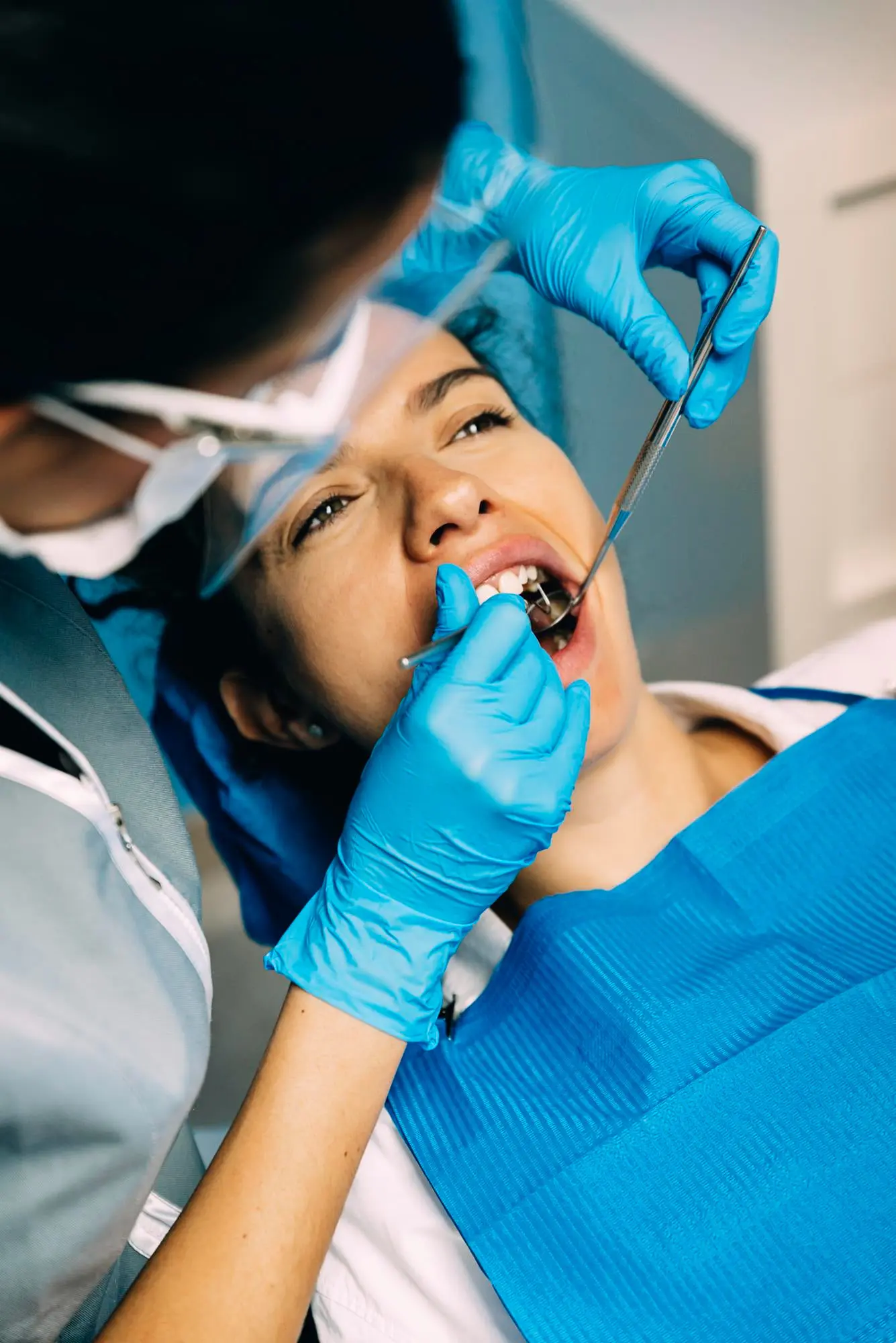 At Emerald City Orthodontics in Kirkland, WA, a dentist in blue gloves checks a patient’s teeth for tongue thrust.