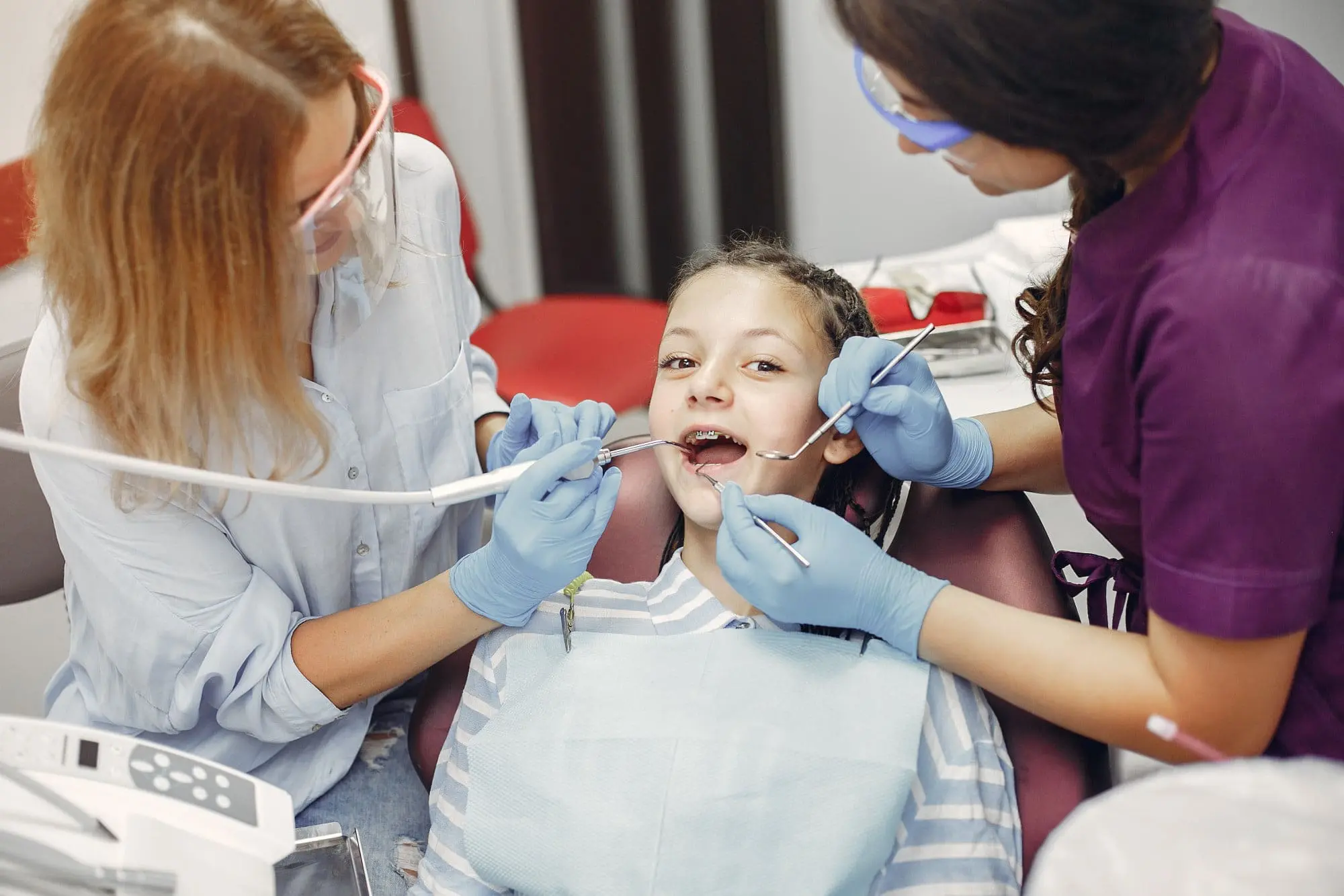 At Emerald City Orthodontics in Kirkland WA, two orthodontists examine a child's open mouth in a dental chair.