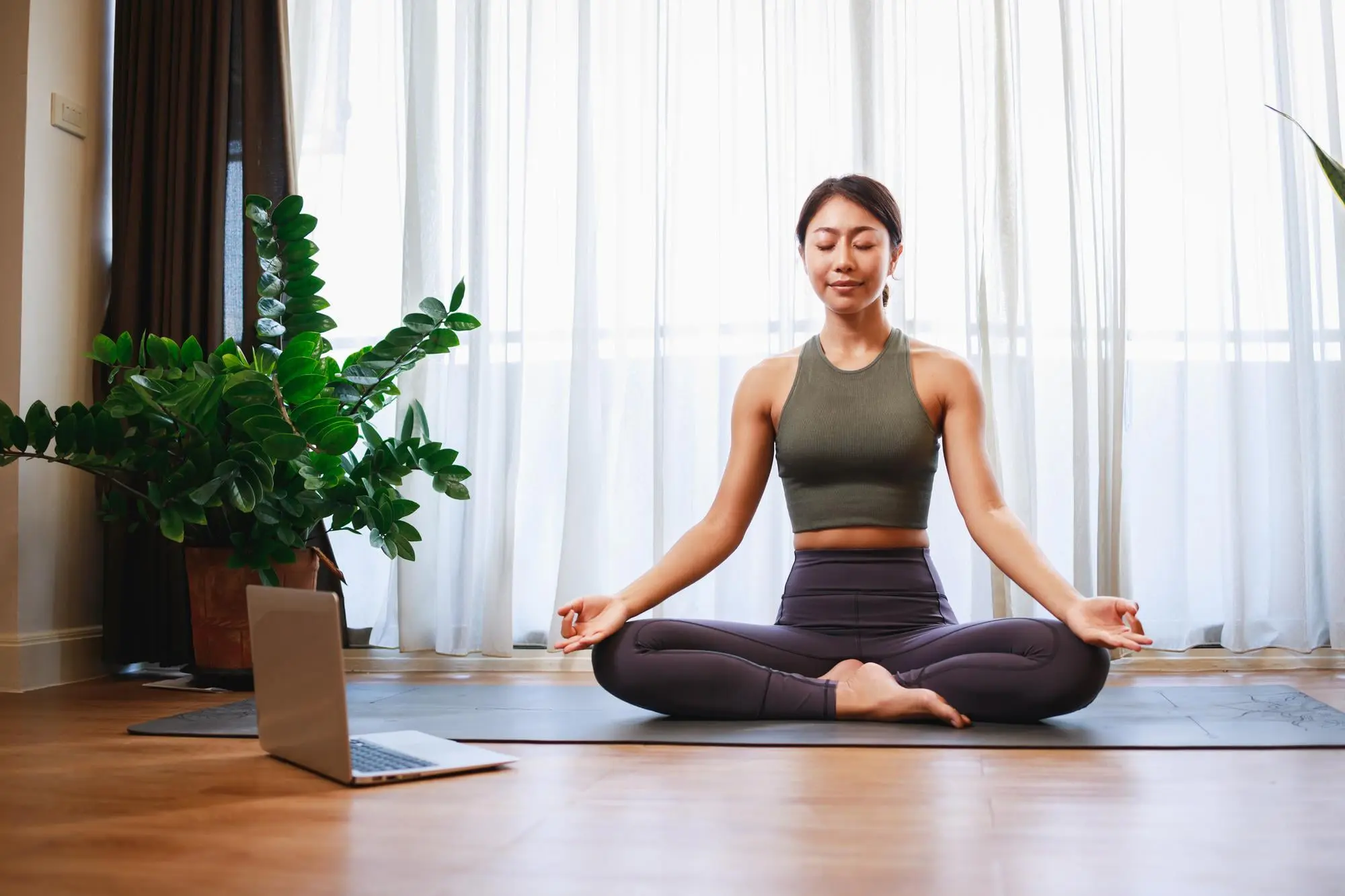 Meditating with eyes closed, a woman sits mouth breather style on a yoga mat at Emerald City Orthodontics in Kirkland, WA.