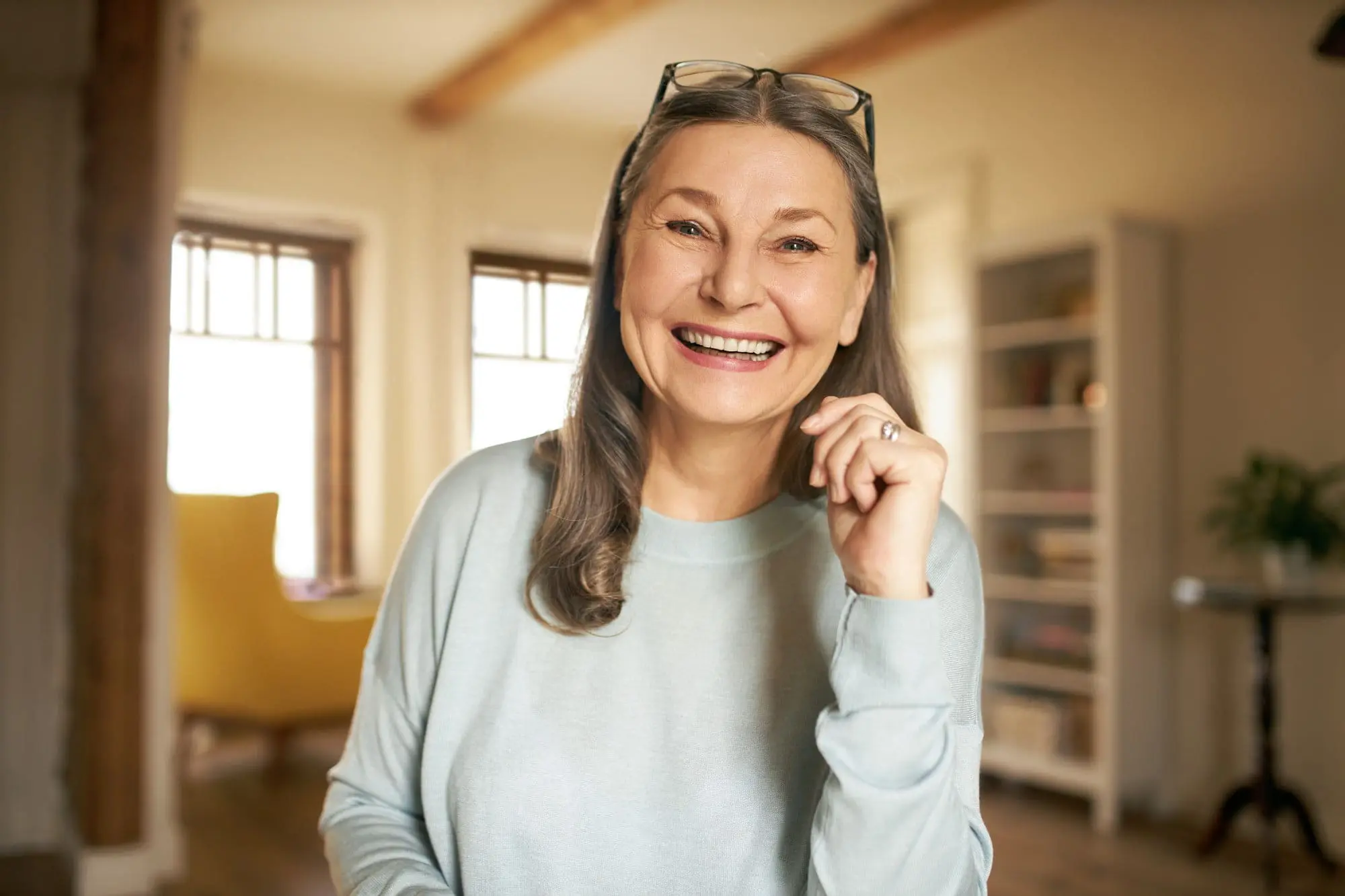 An older woman smiles in a bright living room, confident with Emerald City Orthodontics insurance plans in Kirkland, WA.