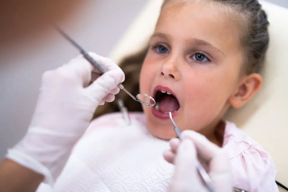 At Emerald City Orthodontics in Kirkland WA, a dentist checks a young girl's teeth for oral habits or tongue thrust.
