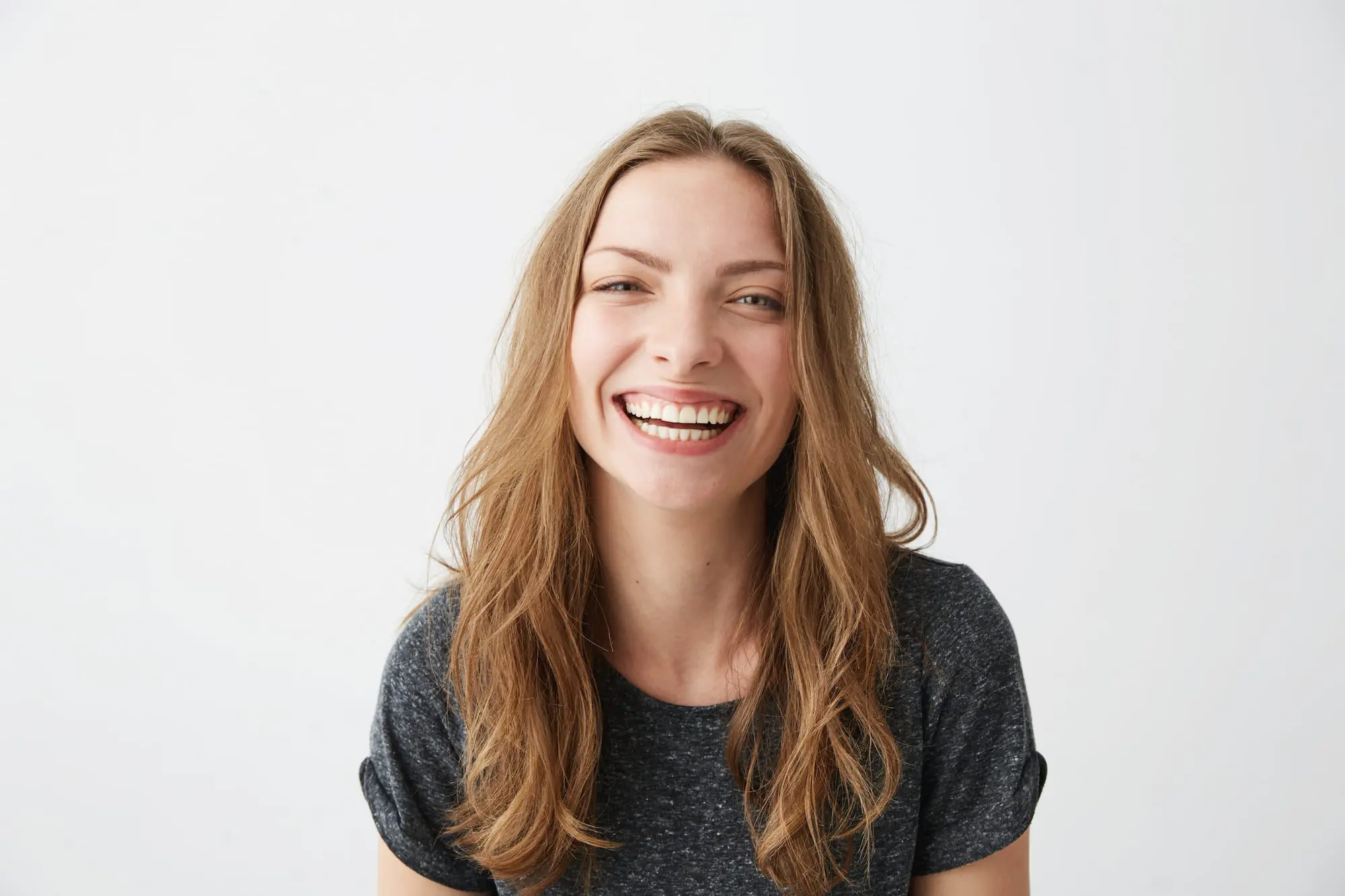 Smiling woman with long light brown hair, representing Emerald City Orthodontics' treatment in Kirkland WA, on white background.