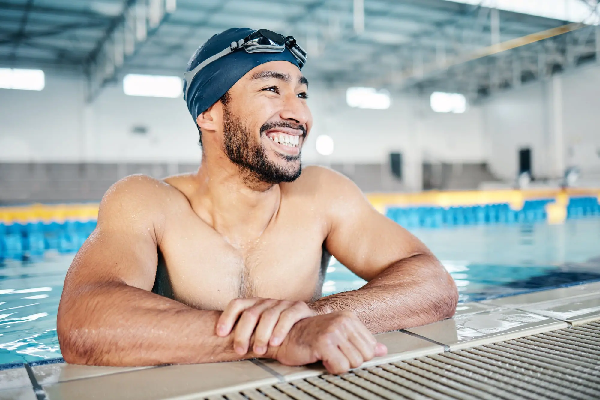 Emerald City Orthodontics Kirkland - Braces & Invisalign A man in swim cap and goggles smiles at an indoor pool, enjoying the affordable braces cost at Emerald City Orthodontics in Kirkland, WA.