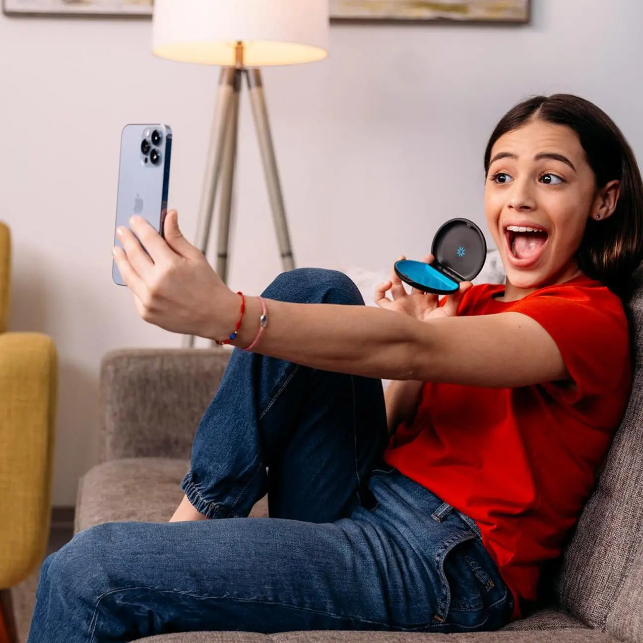 A happy young woman on a couch takes a selfie, reflecting the joy of Emerald City Orthodontics patient reviews in Kirkland, WA.