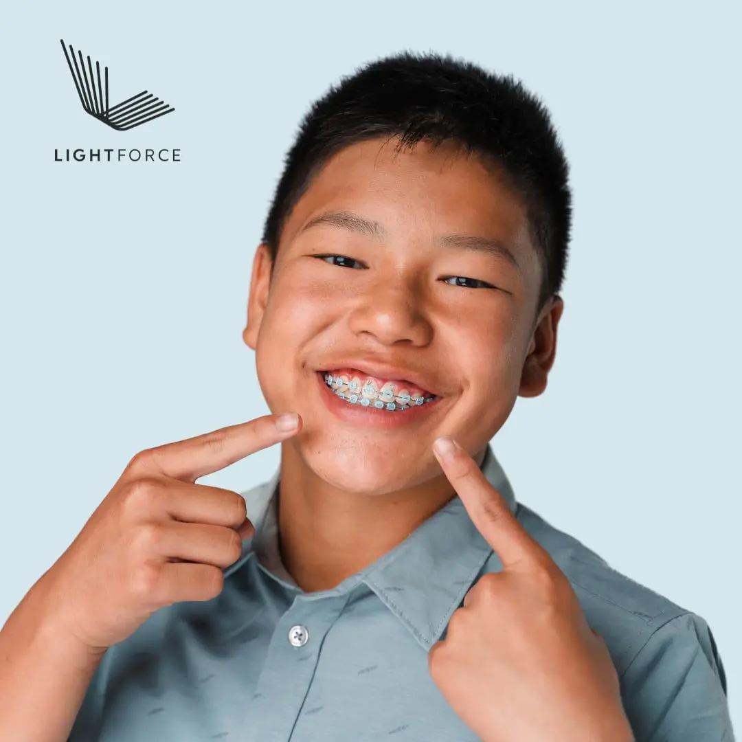 A smiling boy with clear braces points to his teeth; the LightForce logo and Emerald City Orthodontics in Kirkland, WA are visible.