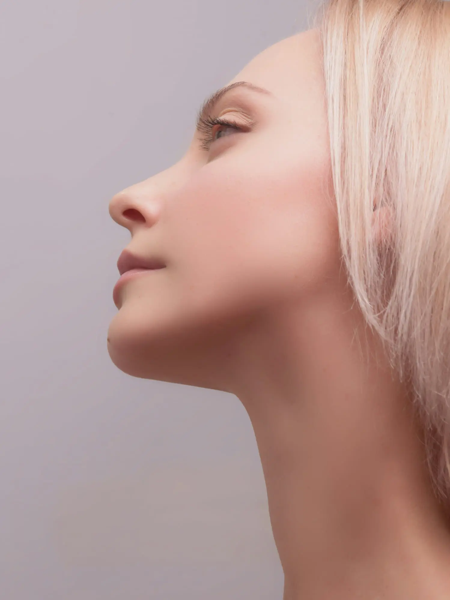 A woman with fair skin and blonde hair is shown in profile, highlighting jawline results at Emerald City Orthodontics in Kirkland, WA.