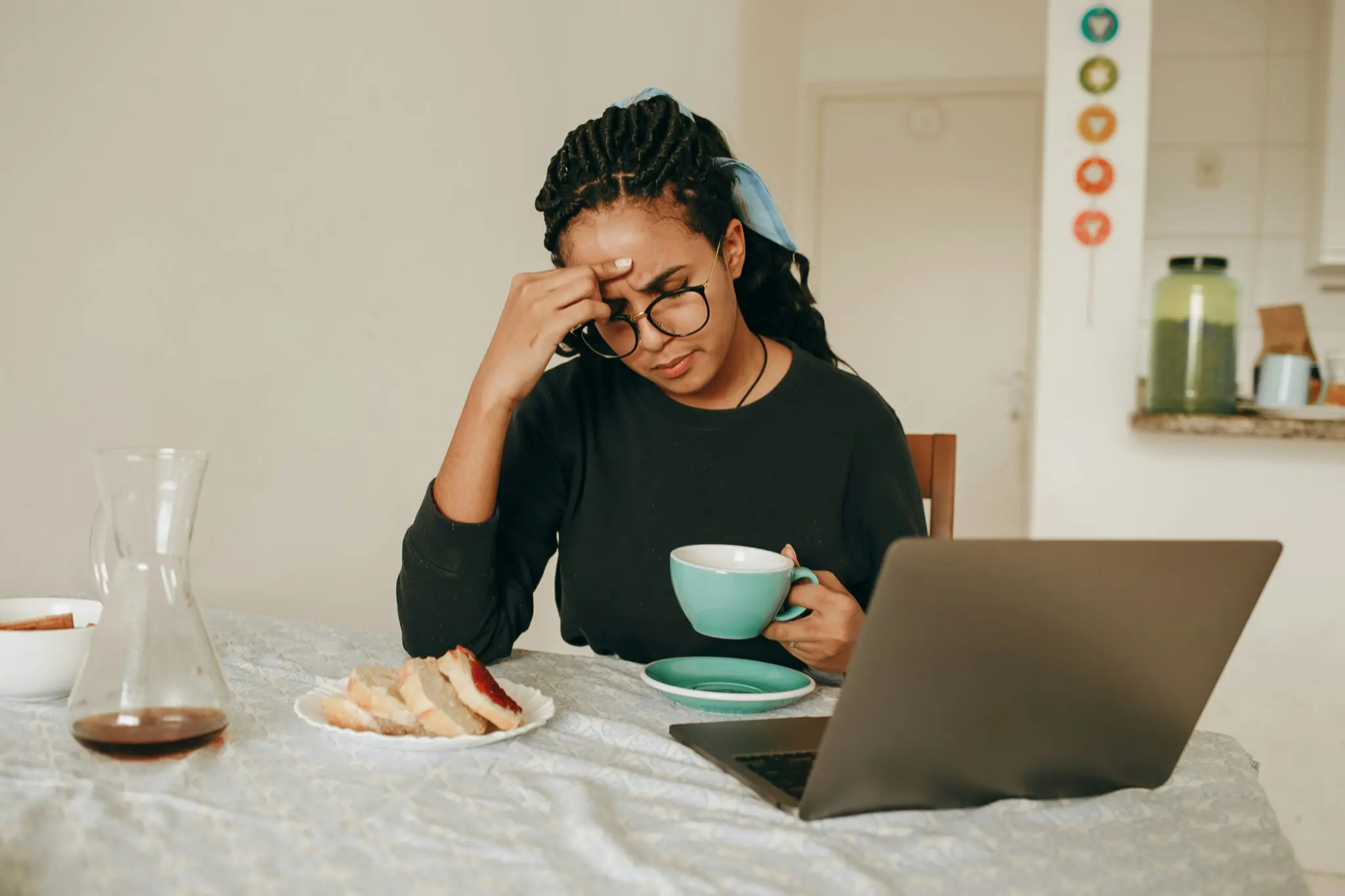At Emerald City Orthodontics in Kirkland, WA, a stressed woman with brain fog sits at a table with a laptop, coffee, and food.