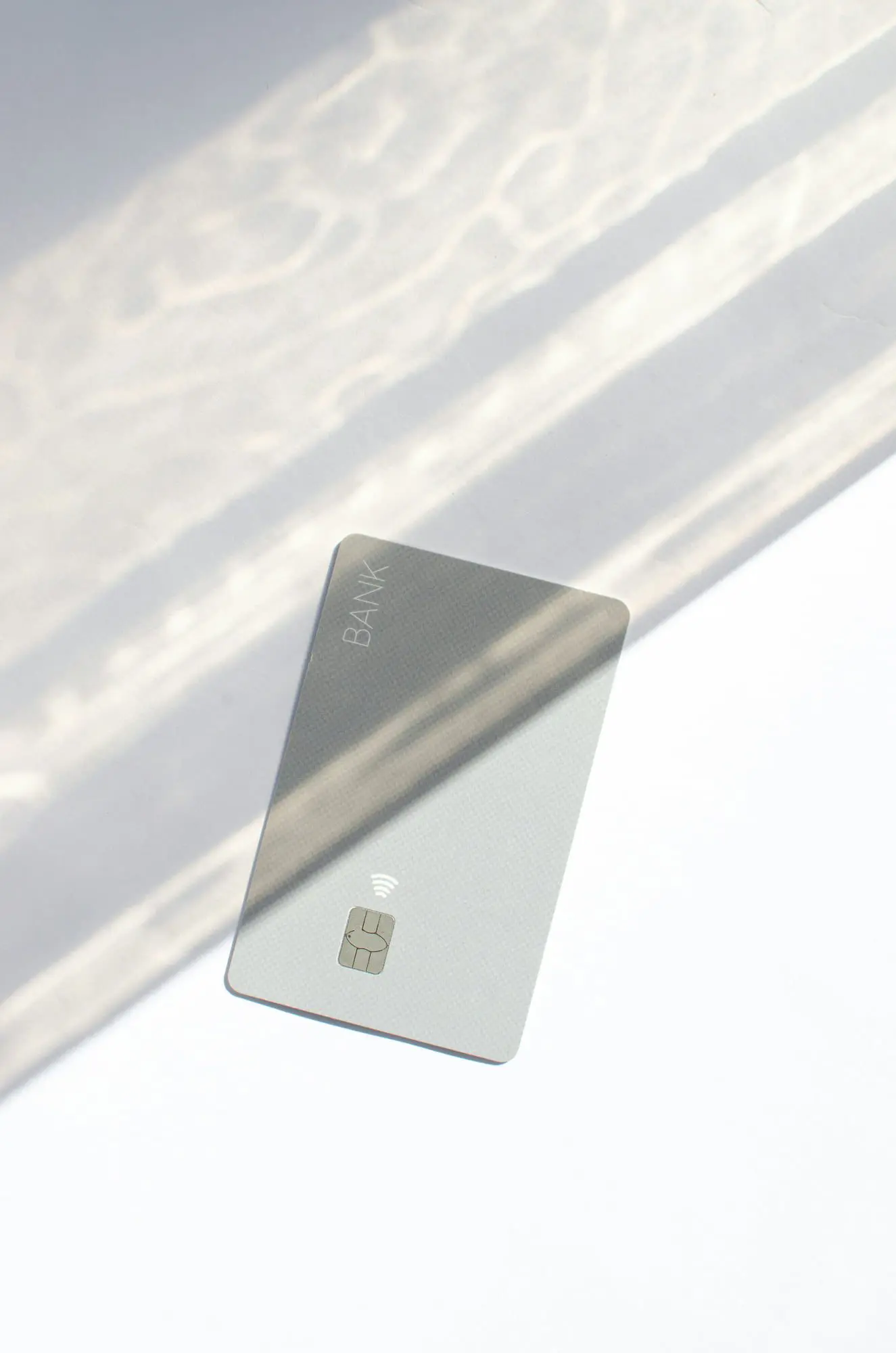 A silver "BANK" contactless credit card on a white surface suggests Emerald City Orthodontics' flexible Invisalign payments in Kirkland, WA.