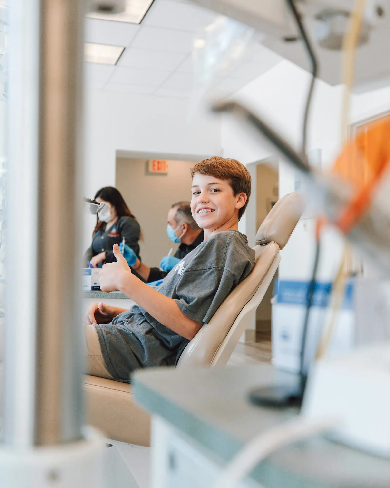Smiling teen gives thumbs up in dental chair at Emerald City Orthodontics in Kirkland WA, showing Tongue Thrust therapy progress.